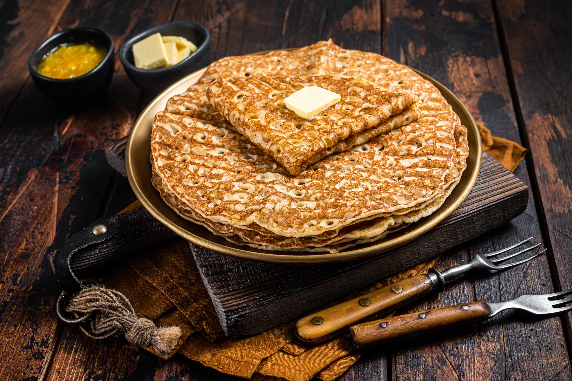 Crepes, Russian Blini with butter on a plate. Wooden background. Top view