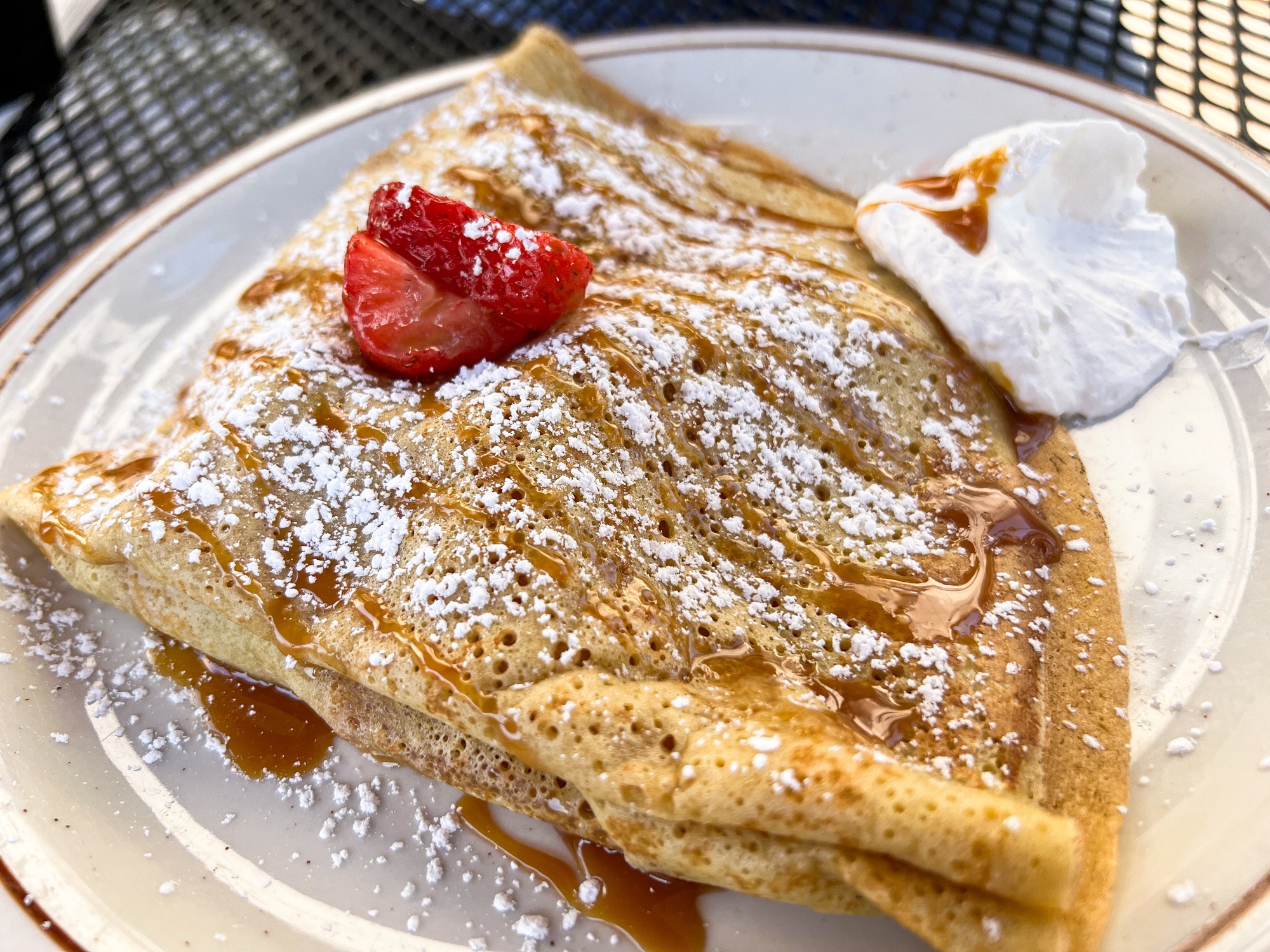 Duice De Leche Caramel, powdered sugar with chantilly cream sweet crepe on plate with strawberry.